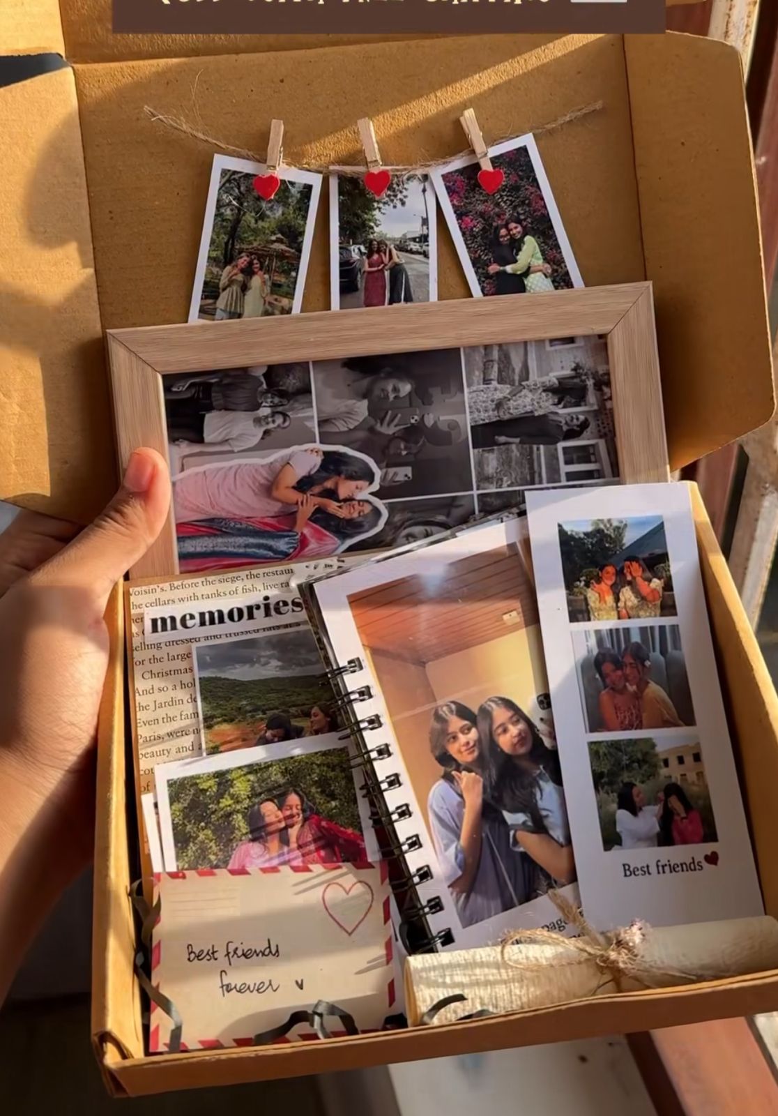 Handmade gift box filled with printed photographs and a small spiral-bound photo album labeled “memories,” with photos clipped inside and arranged neatly to showcase special moments.